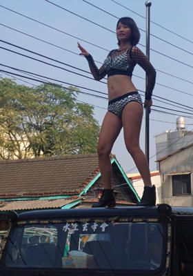 This picture taken on January 3, 2017 shows a pole dancer performing on top of a jeep during the funeral procession of former Chiayi City county council speaker Tung Hsiang in Chiayi City, southern Taiwan. Fifty pole dancers clad in black bikinis gave one Taiwan politician a raucous final send-off in an eyebrow-raising funeral parade that jammed traffic and drew crowds of onlookers.  / AFP / STR / Taiwan OUT        (Photo credit should read STR/AFP/Getty Images)